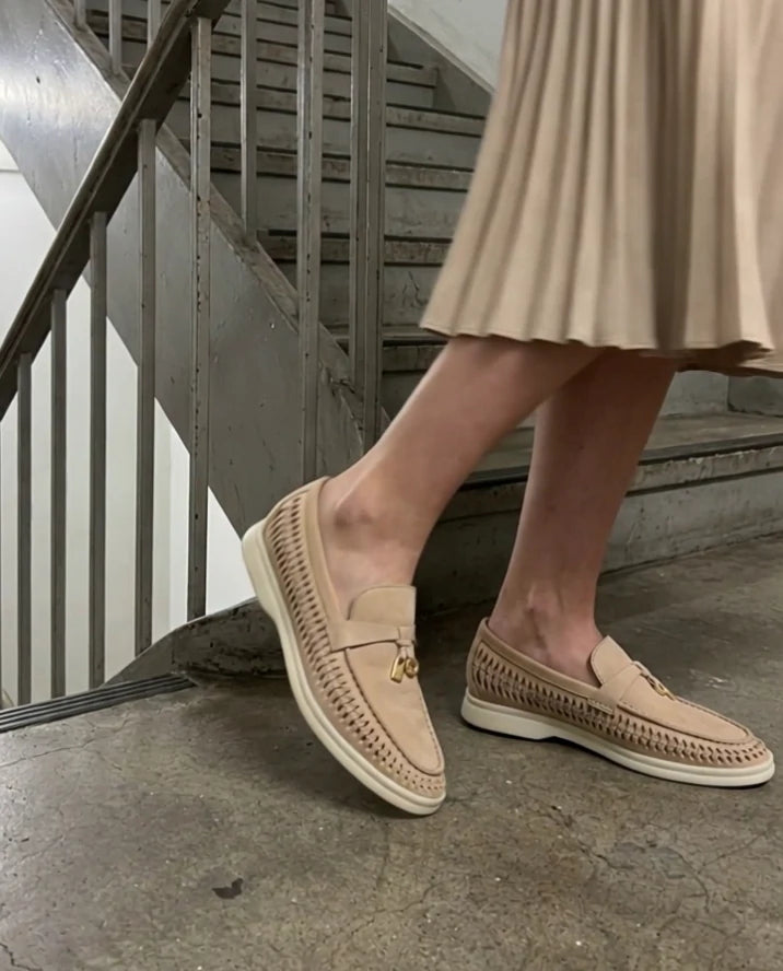 Sand Aureline loafers styled with a pleated skirt on a curved stairwell landing
